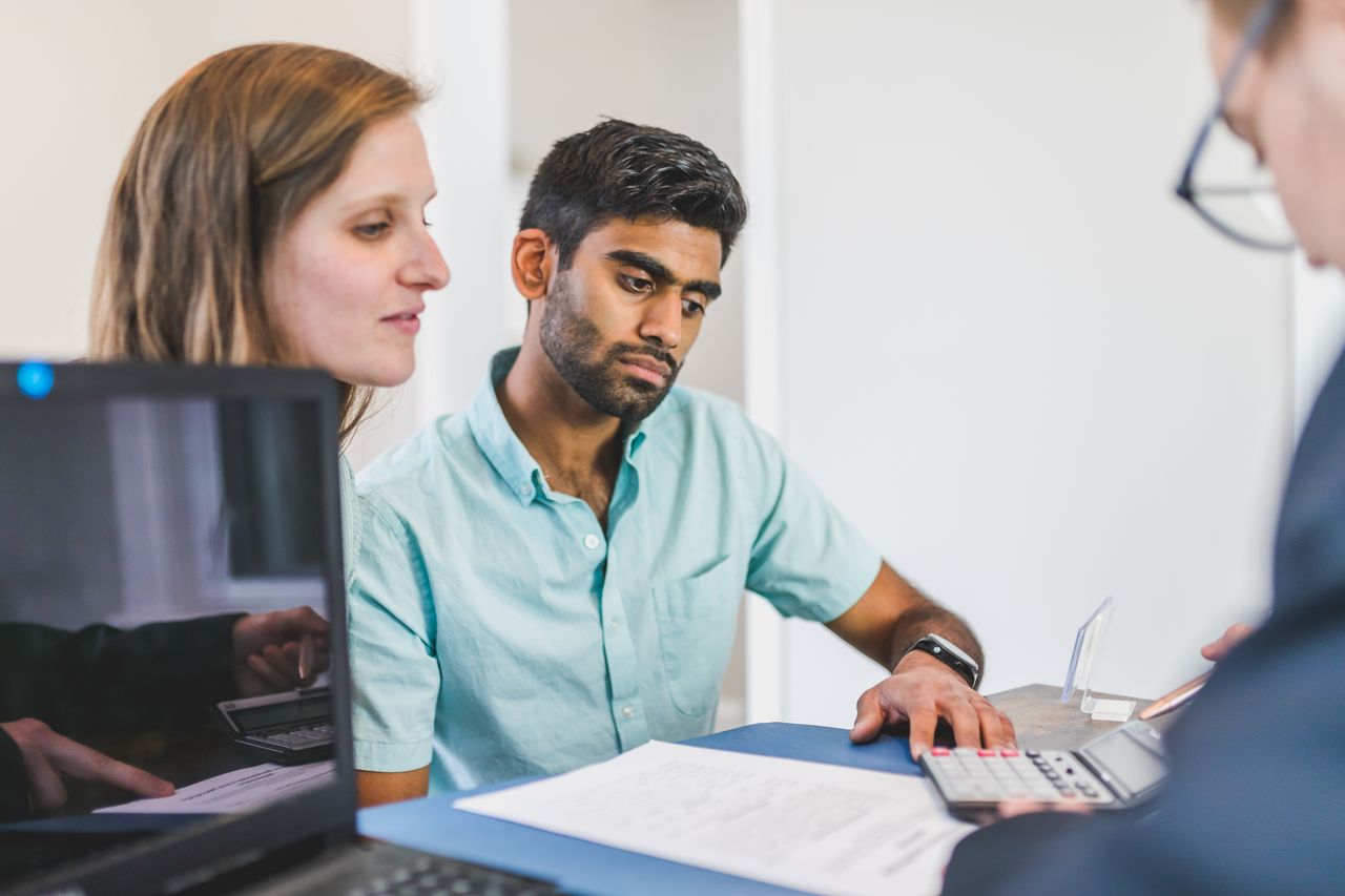 A young couple in discussion with a real estate agent in a modern office setting.